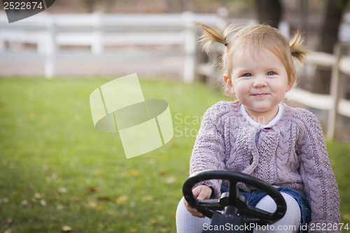 Image of Young Toddler Smiling and Playing on Toy Tractor Outside