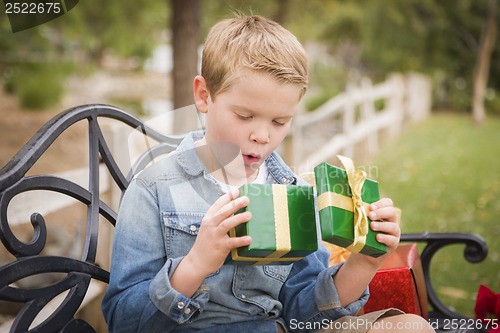 Image of Suprised Young Boy Opens Christmas Gift Outside