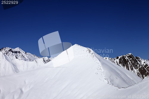Image of Snowy off-piste slope and blue clear sky at nice winter day