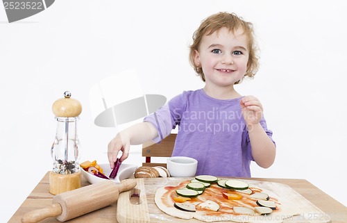 Image of smiling young girl preparing fresh pizza