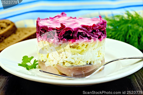 Image of Herring with vegetables in white plate with a fork on the board