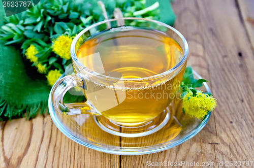 Image of Herbal tea in a cup with a bouquet of Rhodiola rosea on the boar