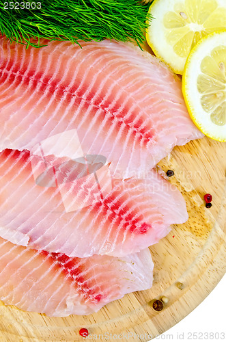 Image of Fillets tilapia with lemon and dill on a round board