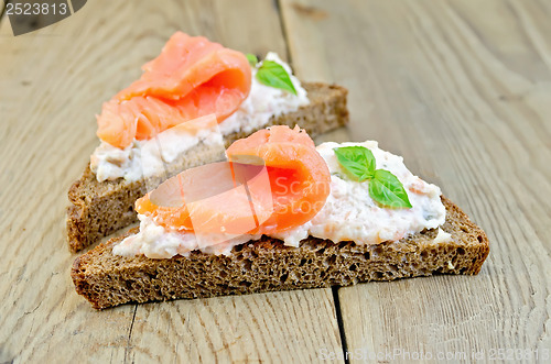 Image of Sandwiches on bread with salmon and basil on board