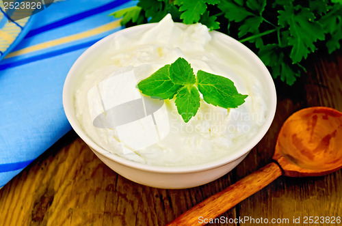 Image of Yogurt in a white bowl with a wooden spoon