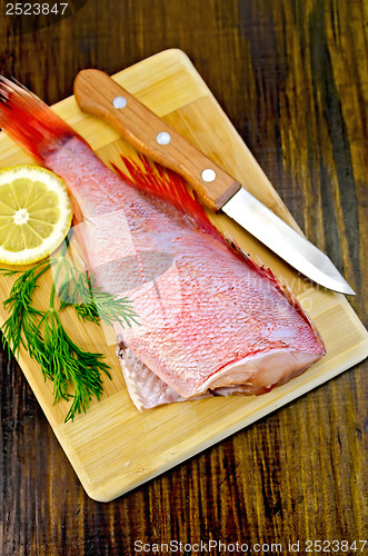 Image of Fillet of sea bass with dill and knife on board