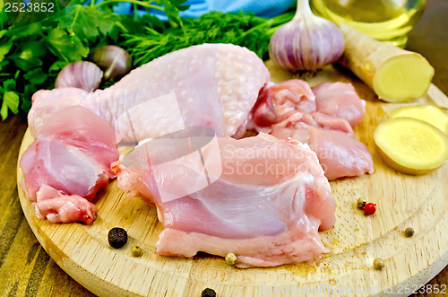 Image of Chicken leg cut on a wooden board with ginger