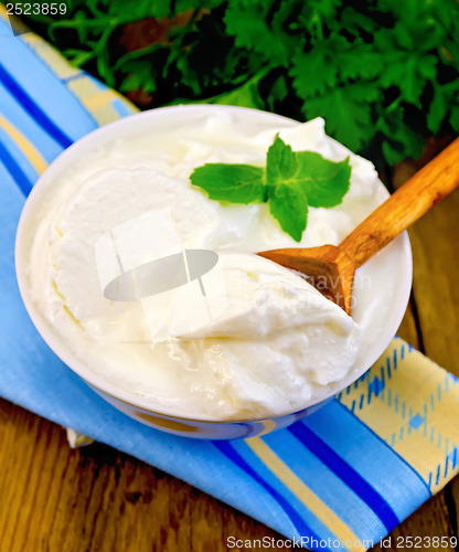 Image of Yogurt in a white bowl with a wooden spoon and mint