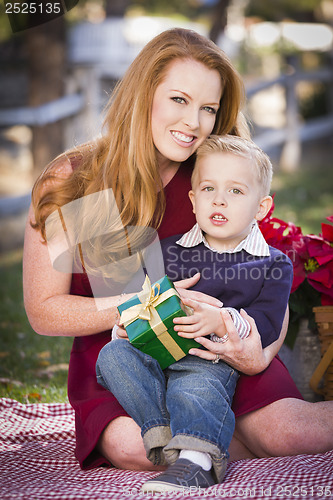 Image of Young Boy Holding Christmas Gift with His Mom in Park