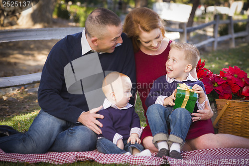 Image of Small Young Family Opening Christmas Gifts in the Park