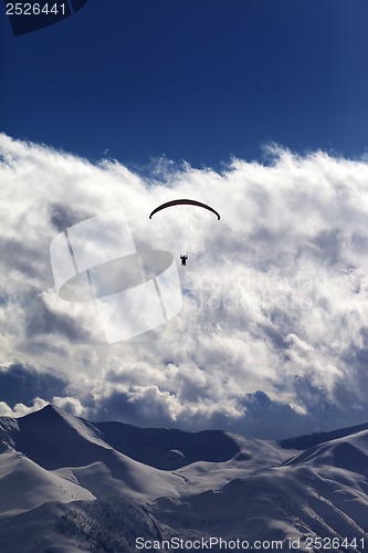 Image of Winter mountains with clouds and silhouette of parachutist