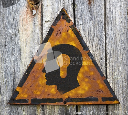 Image of Head with a Keyhole Icon on Rusty Warning Sign.