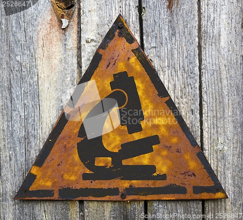 Image of Microscope Icon on Weathered Warning Sign.