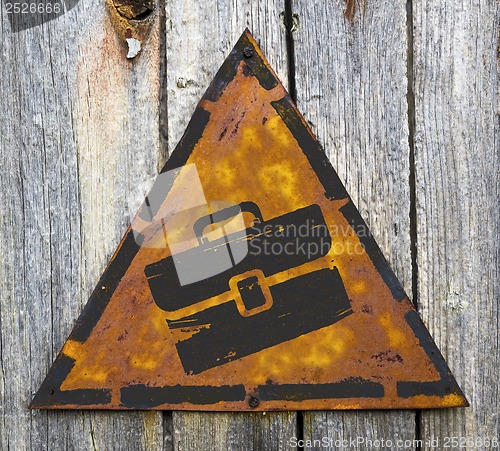 Image of Briefcase Icon on Rusty Warning Sign.