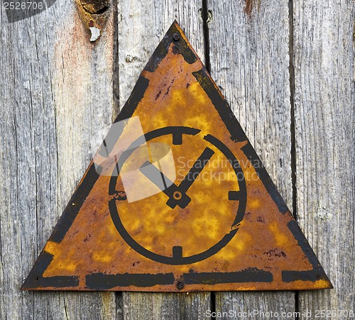 Image of Icon of Clock Face on Rusty Warning Sign.