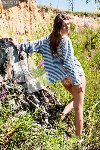 Image of Young beautiful woman on stump