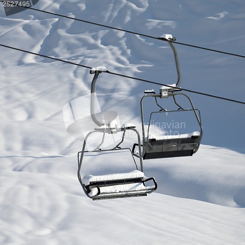Image of Two chair-lift with snowdrift in sun morning. Close-up view.