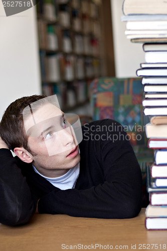 Image of Student Looking Up At Pile of Books