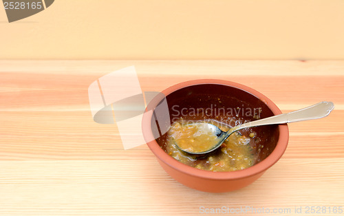 Image of Empty bowl of soup with a spoon on a wooden table 