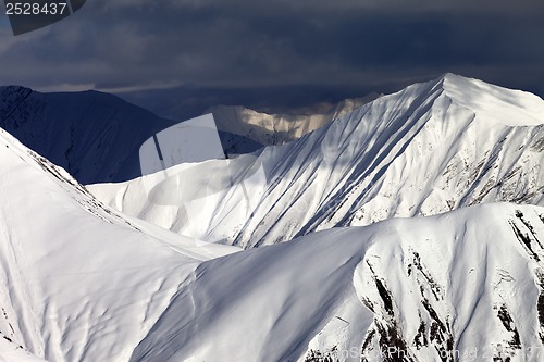 Image of Snowy sunlit mountains and overcast sky