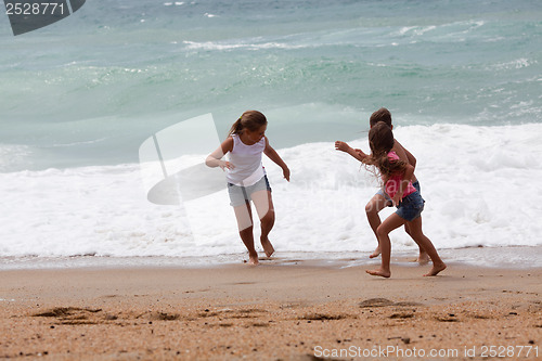 Image of Three children running at the beach