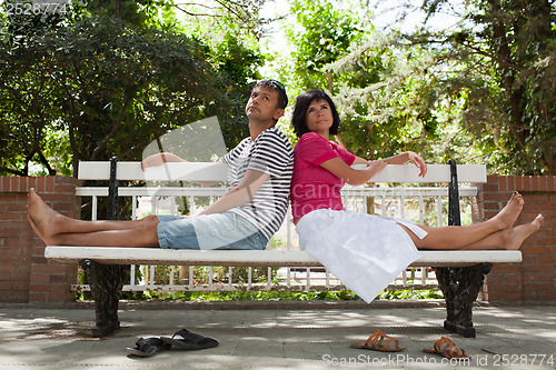 Image of Happy couple sitting on bench in the park