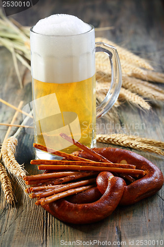 Image of Pretzel, salty sticks and a glass of beer.