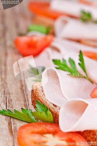 Image of bread with sliced ham, fresh tomatoes and parsley