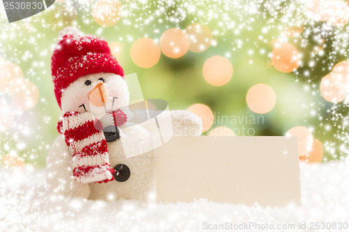 Image of Snowman with Blank White Card Over Abstract Snow and LIght