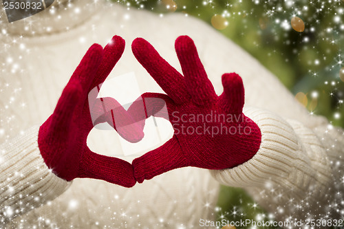 Image of Woman Wearing Red Mittens Holding Out a Heart Hand Sign