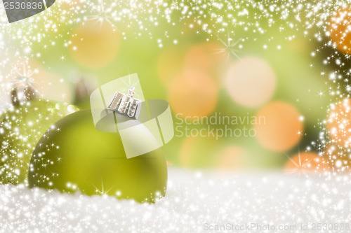 Image of Green Christmas Ornaments on Snow Over an Abstract Background