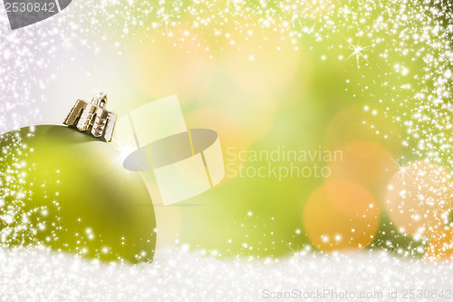 Image of Green Christmas Ornament on Snow Over an Abstract Background