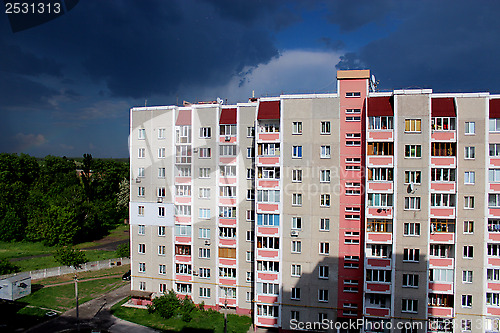 Image of multistorey modern house and very dark rainy clouds