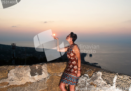 Image of Girl kissing sun at sunset