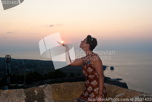 Image of Girl kissing sun at sunset