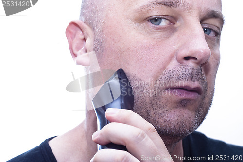 Image of man shaving his beard off with an electric shaver