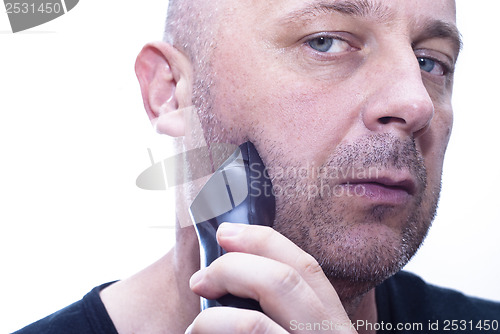 Image of man shaving his beard off with an electric shaver