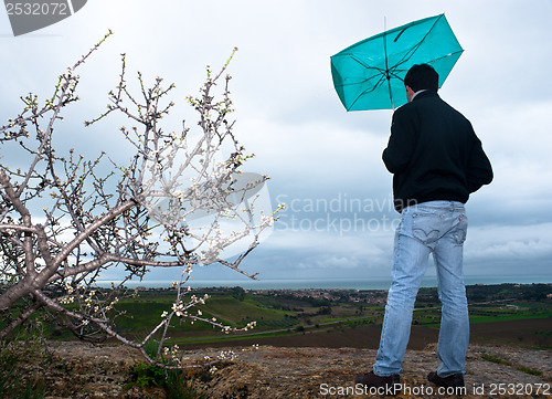 Image of Man with an umbrella look rainstorm clouds