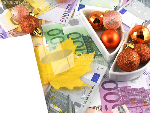 Image of euro notes with christmas balls and autumn leave on it