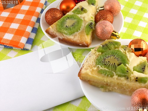 Image of kiwi cake on plate with white blank paper and christmas balls set