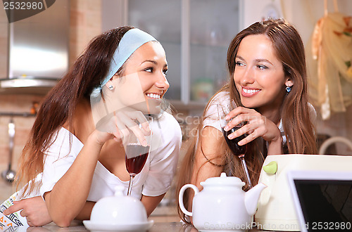 Image of Happy women with wine in kitchen