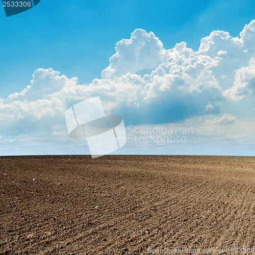 Image of plowed field in spring and clouds over it