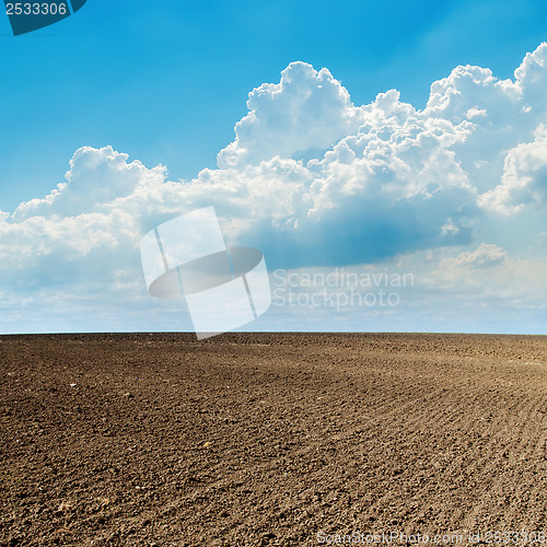 Image of plowed field in spring and clouds over it