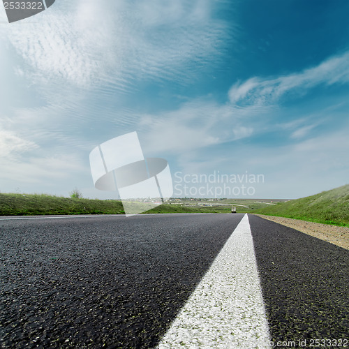 Image of white line on asphalt road and cloudy sky