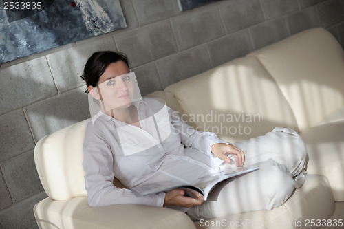 Image of woman reading magazine at home
