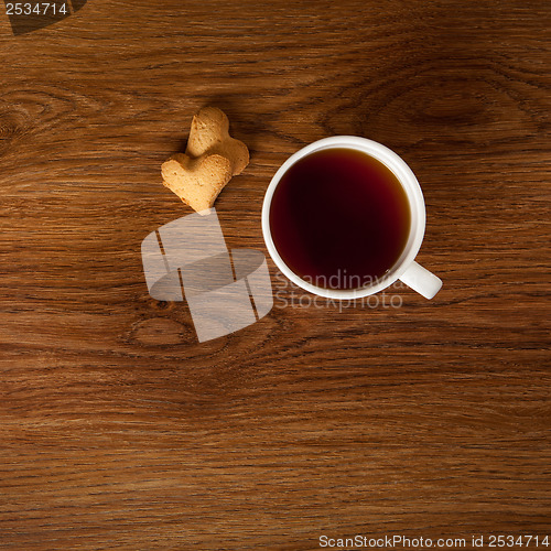 Image of hot cup of tea with cookies on wooden table