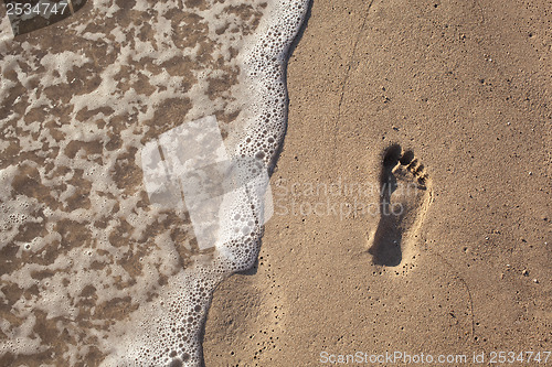 Image of sand with footprint and water wave