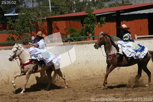 Image of Two Mexican girls in dresses galloping
