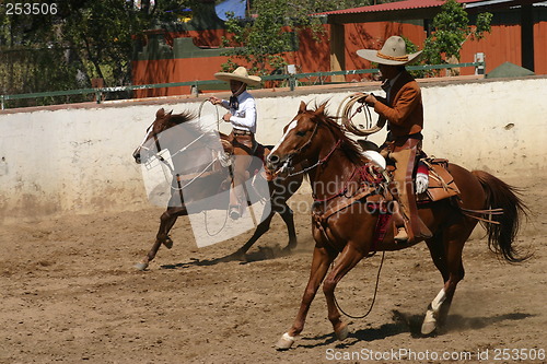 Image of Two charros galloping