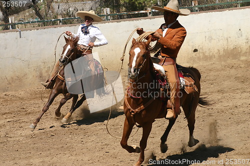 Image of Two charros galloping